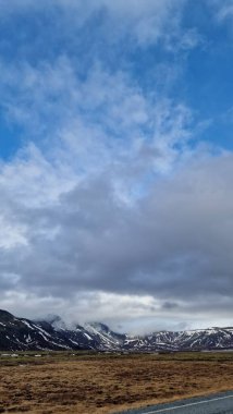 Kuzey Kutbu kırsalındaki görkemli uzun yol manzarası. Tarlaları, karlı tepeleri, İzlanda doğal manzarası. Kuzey manzaralı, manzaralı otoban konsepti.