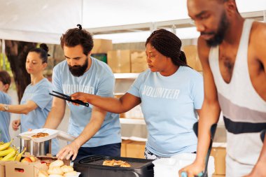 Young volunteers cook and hand out food to the needy. Disabled individuals and multiethnic people come together to provide shelter and humanitarian aid promoting unity and compassion in community.