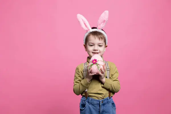 Lilla Leende Unge Presenterar Ett Rosa Målat Ägg Framför Kameran — Stockfoto