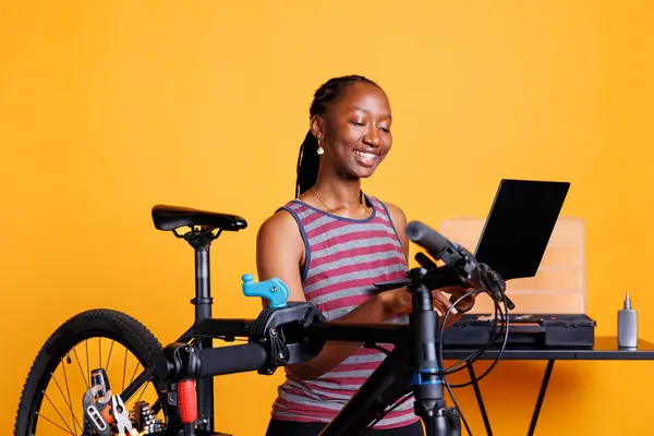 Mujer Negra Enérgica Inspeccionando Fijando Bicicleta Utilizando Ordenador Portátil Kit —  Fotos de Stock