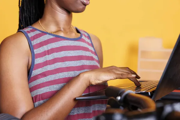 Close-up of african american lady using wireless computer to look for answers to a broken bicycle. Detailed image showcasing sports-loving female browsing for bike equipment on her laptop.