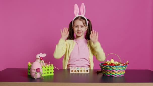 Energetic Young Girl Adorable Bunny Ears Waving Studio Saying Hello — Stock Video