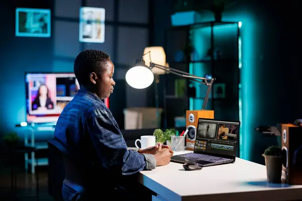 アフリカ系アメリカ人の女性プロデューサーは コンテンツを作成するために机の上に置かれたデジタルラップトップを使用しています 黒人女性はパソコンに集中し 映画制作のためのビデオモンタージュを注意深く分析した — ストック写真