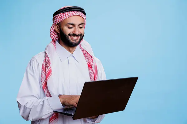 Müslüman Gibi Giyinmiş Gülümseyen Bir Adam Ayakta Durup Dizüstü Bilgisayar — Stok fotoğraf