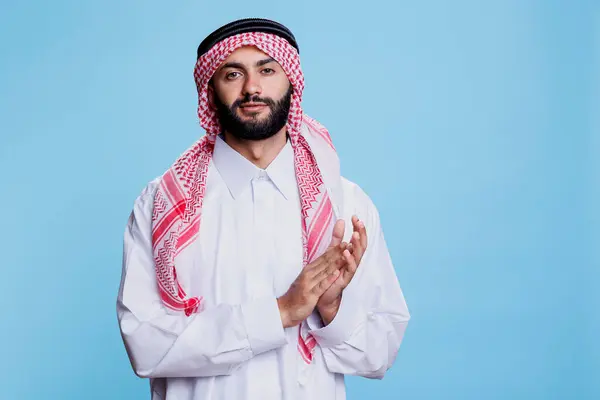 伝統的なイスラム教の服を着た自信のあるイスラム教徒の男性は カメラを見ながら拍手しました 若いアラブ チェッカー ゴートラ ハンド スタジオ 肖像画 — ストック写真