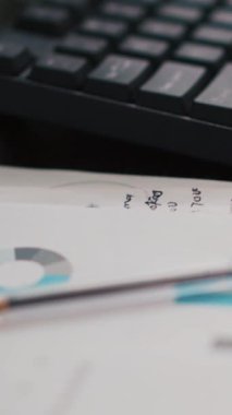 Dikey video klavye ve iş grafikleri ve kazancı gösteren evrak dosyalarındaki rakamlar. Şirket finans bürosundaki kağıt dökümanlarına ilişkin ekonomik yıllık rapor çizelgeleri, kapat