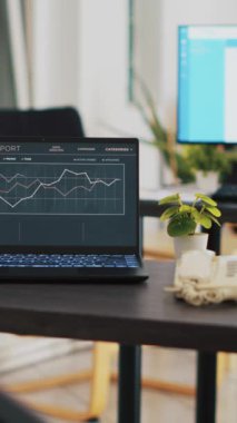 Dikey video işi tahmini grafikleri dizüstü bilgisayardaki kârın çalışma masasında oturduğunu gösteriyor. Mali yıllık gelir istatistikleri ve bankacılık denge özeti rapor muhasebe defterinde ekran