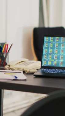 Şirket ofisindeki dikey video bilgisayarı gerçek zamanlı olarak borsa değerlerinin değiştiğini gösteriyor. Not defterinin yanındaki kağıt işi ön bellek alım satım endekslerini ve pasta grafiklerini gösteriyor