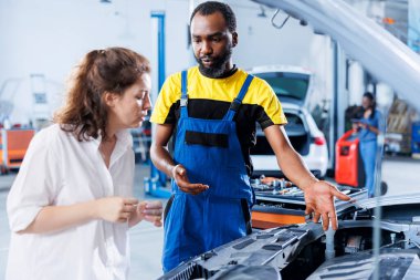 Tamirhanedeki tamirci rutin araç kontrolü yapar, müşteriye gerekli motor tamiri hakkında bilgi verir. BIPOC garaj çalışanı araba bakımını bitirdikten sonra müşteriyle sohbet ediyor.