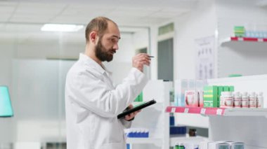 Sağlık çalışanları raflardaki ilaç paketlerini izliyor ve müşterilere mal verilmesini garanti altına almak için mağaza envanterini yönetiyor. İlaç kutularıyla ilgilenen eczane teknisyeni..