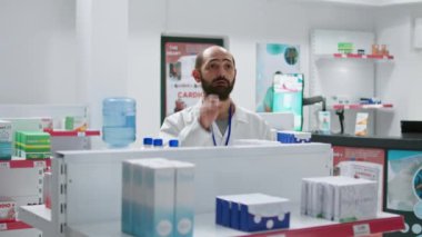 Eczacı hologram projeksiyonunu kullanarak envanter sayımı yapıyor, ilaç ve takviye malzemelerini sayıyor. Eczane çalışanı tıbbi malzeme temin etmeye çalışıyor, yapay zeka. Kamera 1.