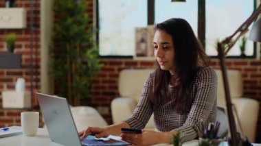 Mutlu kadın online alışveriş yapıyor, dizüstü bilgisayarına kredi kartı bilgilerini dikkatlice yazıyor. Hintli kişi web sitesine ödeme metodu eklerken rahat, sıcak bir evde, kamera B çekimleri
