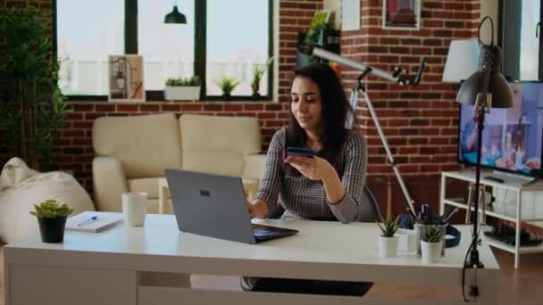 笑着的女人在网上购物 在笔记本电脑键盘上小心地输入借记卡信息 在现代公寓客厅 相机A里 人们在网站上添加支付方法 — 图库视频影像