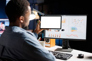 Başlangıç çalışanı tableti beyaz ekranlı tutuyor, mali durumları gözden geçiriyor ve bilgisayardan uzaktan kumandalı raporlar bildiriyor. Genç yetişkin, izole edilmiş boş şablona ve dijital istatistiklere sahip bilgisayar ve aygıt kullanır.