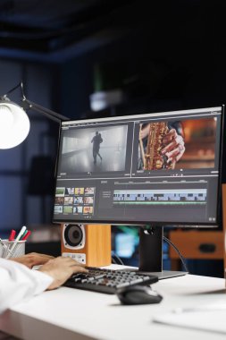 Görüntü ve sesle çalışan erkek görüntü yönetmeni, yeni projeyi düzenleyen, ofis masasında oturan film montajını kesen. Yapım sonrası yazılımda bir adamın bilgisayar işleme filmini kullanmasının ayrıntılı görünümü.