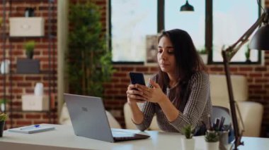 Telesekreter evde laptopun önünde telefon bildirimlerini kontrol ediyor, işe ara veriyor. Konforlu apartman dairesinde çalışan bir kadın akıllı telefondan ve kamera B 'den mesajları okumak için işten ara veriyor.