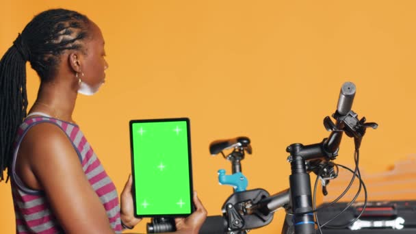 Woman Holds Green Screen Tablet Using Advertise Bike Repair Shop — Stock Video