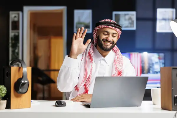 彼の職場に座って イスラム教徒の男がデジタルラップトップで波を起こし ビデオ会議を始めました 彼はテクノロジーに魅了され ミニコンピュータを使って探検し 交流し 研究を行っています — ストック写真