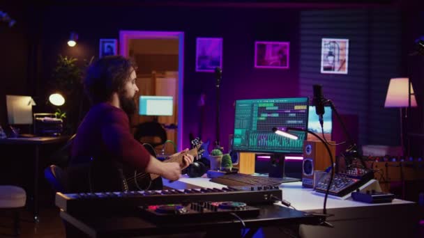 音楽プロデューサーのミキシングギターは 電子サウンドボードコンソールとソフトウェアを使用して 音響楽器で彼によって演奏されます 新しい曲 ホームスタジオを開発する熟練したミュージシャン カメラ — ストック動画