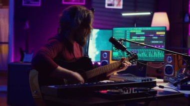 Yaratıcı söz yazarı mikrofonda şarkı söylüyor ve gitarını çalıyor, akustik mühendisliği teknolojisi ve daw yazılımı. Sanatçı enstrümanla müzik yaratıyor ve konsolu karıştırıyor. Kamera A.