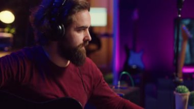 Ses mühendisi akustik gitar çalıyor ve müzik kaydetmek için karıştırma konsolu kullanıyor, sesi ayarlıyor ve melodilere ses efektleri ekliyor. Sanatçı dijital ses çalışma istasyonu yazılımıyla çalışıyor. Kamera A.