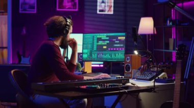 Elektronik piyano klavyesi ve kayıt sesleri çalan ses mühendisi, yeni melodiler yaratmak için karıştırma konsolu ve daw yazılımı kullanıyor. Müzik endüstrisi uzmanı ev stüdyosunda stereo aletler kullanıyor. Kamera A.