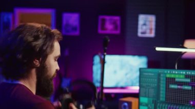 Müzik yapımcısı ses seviyelerini ayarlamak ve bir ses kaydı yapmak için elektronik piyano notaları çalıyor. Yaratıcı sanatçı yeni şarkılarını kendi stüdyosunda hazırlıyor. Kamera B.