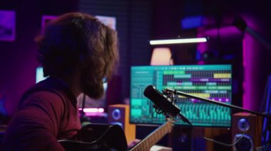 Yoğunlaştırıcı mikrofonlu sanatçı gitarda bir şarkı besteleyerek müziği karıştırıp ustalaştırmaya çalışıyor. Yapımcı kayıt melodileri ve prodüksiyon sonrası ses efektleri ekliyor. Kamera B.
