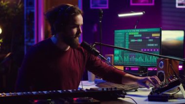 Ses mühendisi elektrikli sentezleyicinin tuşlarına basıyor ve yeni müzik kaydediyor, ses seviyesini ayarlıyor. Sanatçı mikrofonda şarkı söylüyor. Ev stüdyosunda miksaj masasında çalışıyor. Kamera A.