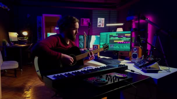 ホームスタジオでは 音楽エンジニアがアコースティックギターを練習し 曲を書き 増幅デバイスや音楽ツールで楽しんでいます 曲を作る熟練したミュージシャン カメラ — ストック動画