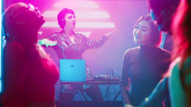 Korkak kadın DJ kulüpte sahnede sesleri karıştırıyor, müzik istasyonunda arkadaşlarıyla dans ediyor. Genç bir kadın farklı insanlarla zıplıyor, gece kulübünde eğleniyor. Üçayak atışı.