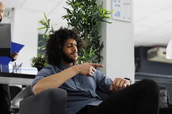Punctual arab start up company manager checking time on wristwatch in business office. Smiling young businessman looking at watch on hand, showing corporate productivity concept