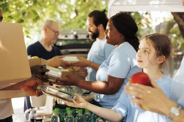 stock image Charity group, including men and women of different ages and ethnicities, together providing donations and support for food drive. Volunteers hand out canned goods and essential items to the needy.