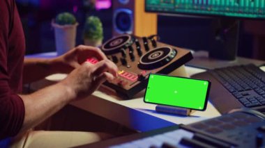 Müzisyen, telefon ekranında çalışan yeşil ekran, karıştırma konsolu ile karışık sesler ve melodiler yaratıyor. Sanatçı bilgisayarda eşitleyici ve daw yazılımı kullanarak yeni notlar kaydediyor. Kamera A.