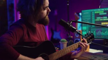 Şarkı sözü yazarı, akustik gitarıyla kendi stüdyosunda akorları söylemek için mikrofon kullanıyor. Ses mühendisi yeni müzik bestelemek için ses panosu ve dengeleyiciyle çalışır. Kamera A.