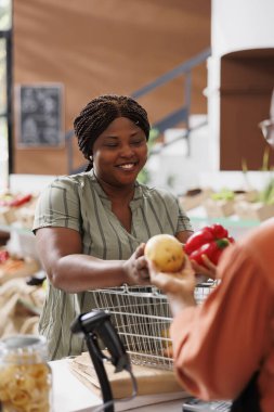 Afro-Amerikan kadın bireyler sağlıklı yemek tarifleri için yerel olarak yetişmiş organik sebzeler alıyor. Genç tüketici yerel tedarikçiye tartılması ve paketlenmesi için taze ürün veriyor.