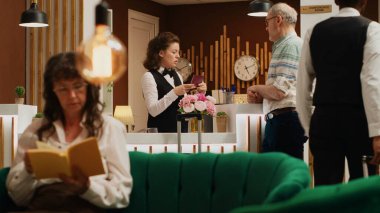 Çalışan, oteldeki pasaport bilgilerini onaylıyor, uçuştan sonra resepsiyona gelen yaşlılar için kontrol sürecini kolaylaştırıyor. Resepsiyon görevlileri gezginden kimlik belgesi alıyor. El kamerasıyla..