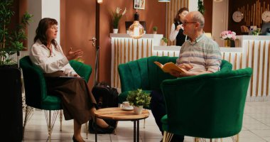 Yaşlı bir çift otel odasının girişini beklerken tatil planlarından bahseder. Emeklilik tatili için sınırlı bir seyahat programı oluşturan karı koca, interneti kontrol ediyor.