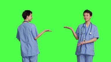 Stüdyoda tanıtım reklamı için bir şey sunan sağlık uzmanı yeşil perde arkaplanına karşı bir şeye işaret ediyor. Tıbbi asistan internet reklamı yapıyor, sağlık uzmanı. Kamera B.