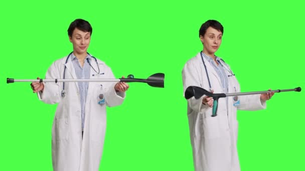在骨折 康复和受伤后康复的情况下 有拐杖的女医生可用来帮助行动 医生把矫形器的工具放在绿屏上 摄像头B — 图库视频影像