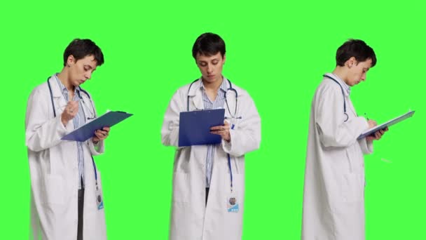 在绿屏背景下 医生在病人检查后做笔记 写下治疗疾病的药物 医生穿着白衣 用剪贴板纸做检查 摄像头B — 图库视频影像