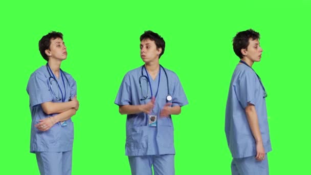 冷漠的护士在诊所等病人时表现得很沮丧 她站在绿屏的背景下 忧心忡忡的护士 蓝色的刷子等着人们来检查 摄像头B — 图库视频影像