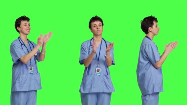 微笑的医疗助理为工作室里的某个人喝彩 庆祝成功 并在绿屏的背景下欢呼 年轻的护士拍手 为自己的成就感到高兴 摄像头B — 图库视频影像