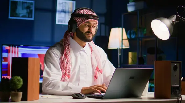 Lachende Arabische Man Met Draadloze Koptelefoon Thuis Woonkamer Typt Berichten — Stockfoto