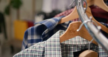 Üst sınıf moda butik mağazalarında yeni koleksiyonlardan moda giysiler sergilenen şık tişörtlerin son derece yakın plan çekimi. Erkek gömlekleri mağaza raflarında dönüyor.
