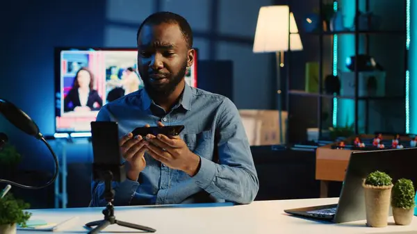 アフリカ系アメリカ人のテクノロジーコンテンツクリエイターが新しくリリースされたスマートフォンのレビューを撮影し 聴衆に挨拶し 電話仕様に関するフィードバックを提示し — ストック写真