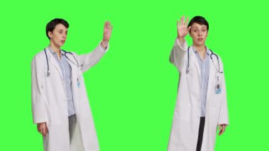 Kadın doktor selam veriyor ve insanları check-up 'a davet ediyor, hastaları daha yakına davet ediyor ve onları selamlıyor. Yeşil ekrana karşı beyaz önlüklü ve steteskoplu yetenekli bir doktor. Kamera B.