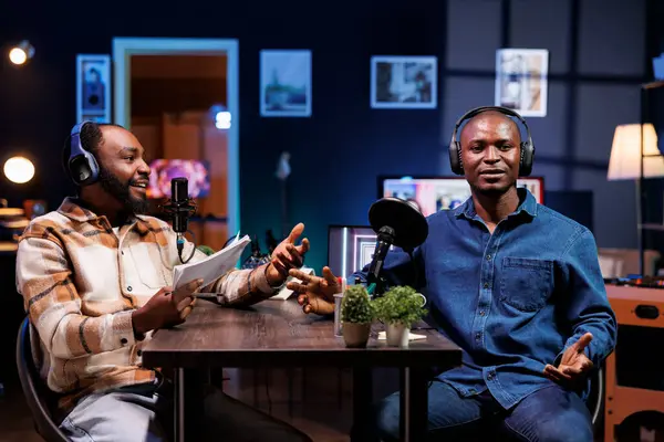 stock image Live talk show is hosted by a dynamic duo discussing various topics and interacting with fans. Black men using professional microphones to produce high quality content for online streaming service.