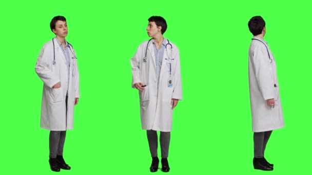 女专家看着手机手表等着病人来参加考试 在工作室的绿屏背景下 穿白衣的全科医生表现得不耐烦 相机A — 图库视频影像