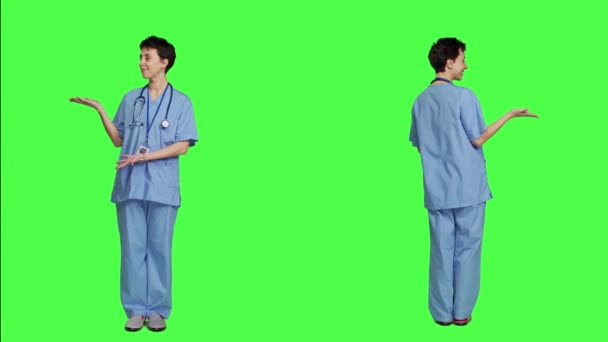 スタジオでプロモーション広告のためのものを提示するヘルスケアの専門家は 緑色の背景に何かを指摘します ウェブコマーシャル 健康に関する専門知識を作成する医療アシスタント カメラ — ストック動画